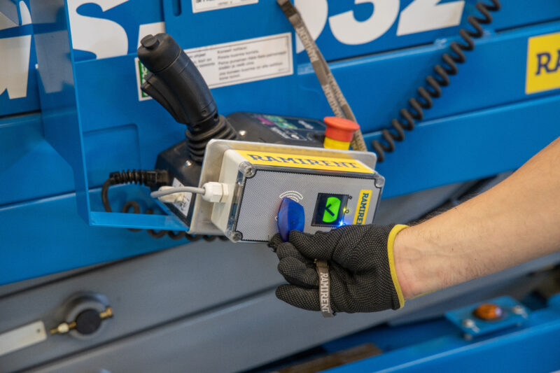 Hansikaskäsi pitelee muovitägiä RamiSmartin lukijalaitteen kyljessä.