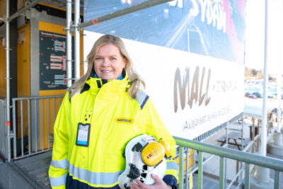 Työmaa-asuinen nainen katsoo hymyillen kameraan.