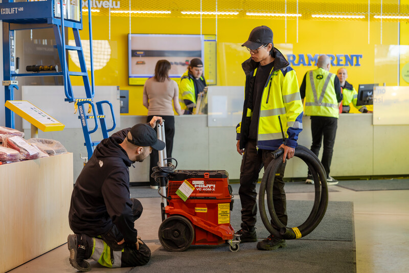 Vuokraamon työntekijä ja asiakas tutkivat Hiltin punaista konetta.