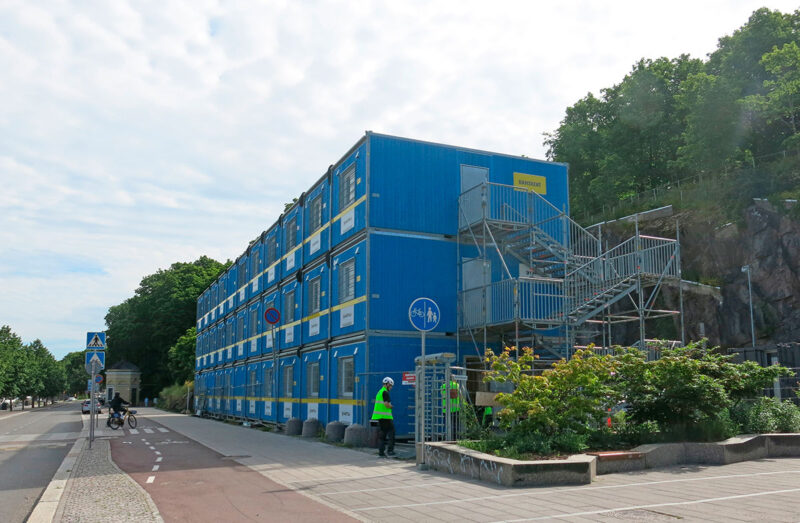 Sinisiä RamiWide-työmaatiloja kolmessa kerroksessa kadun varrella.