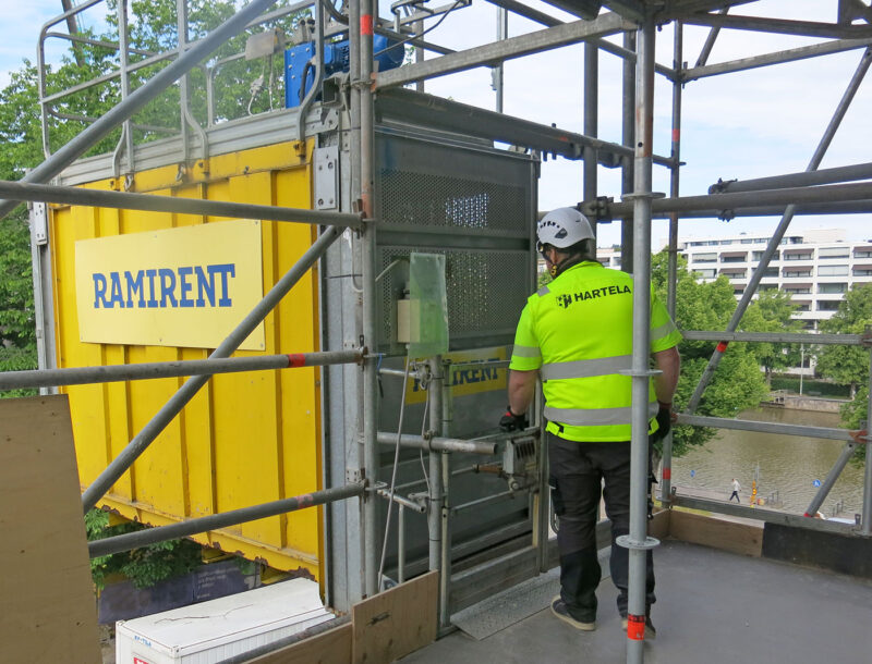 Työasuinen mies astuu keltaiseen työmaahissiin.