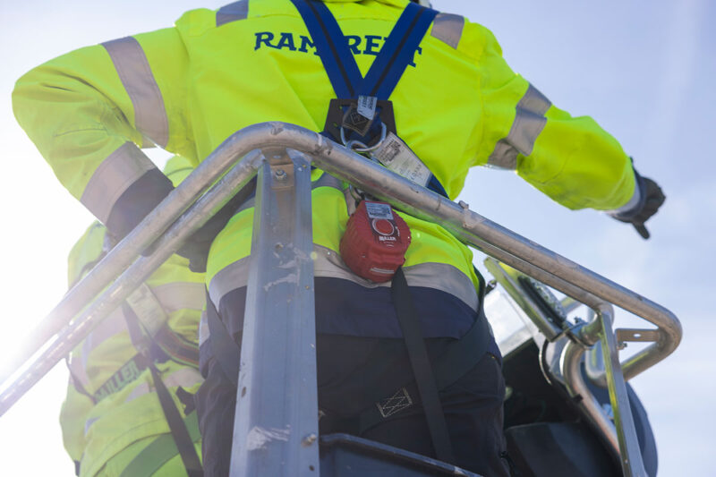 Henkilönostimen korissa seisoo selkä kameraan päin henkilö joka on pukenut päälleen turvavaljaat.