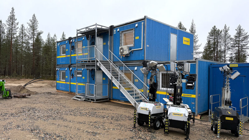 Kolme valomastoa työmaalla kahteen kerrokseen asennettujen työmaatilojen edessä.