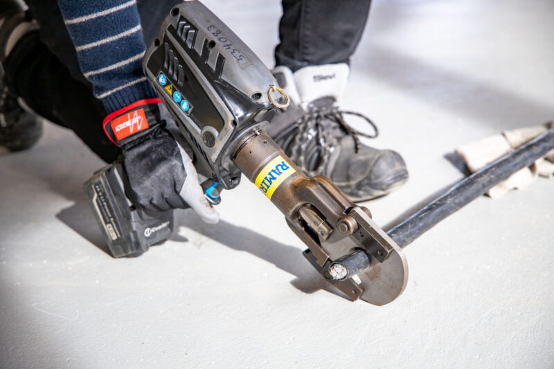 Henkilö leikkaa kaapelia Ramirentin kaapelileikkurilla.