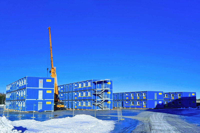 Sinisiä työmaatiloja kahdessa ja kolmessa kerroksessa lumisessa maisemassa.