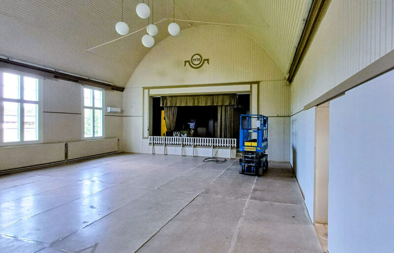 Sininen henkilönostin isossa salissa, jossa on suuret ikkunat ja kaareva katto.