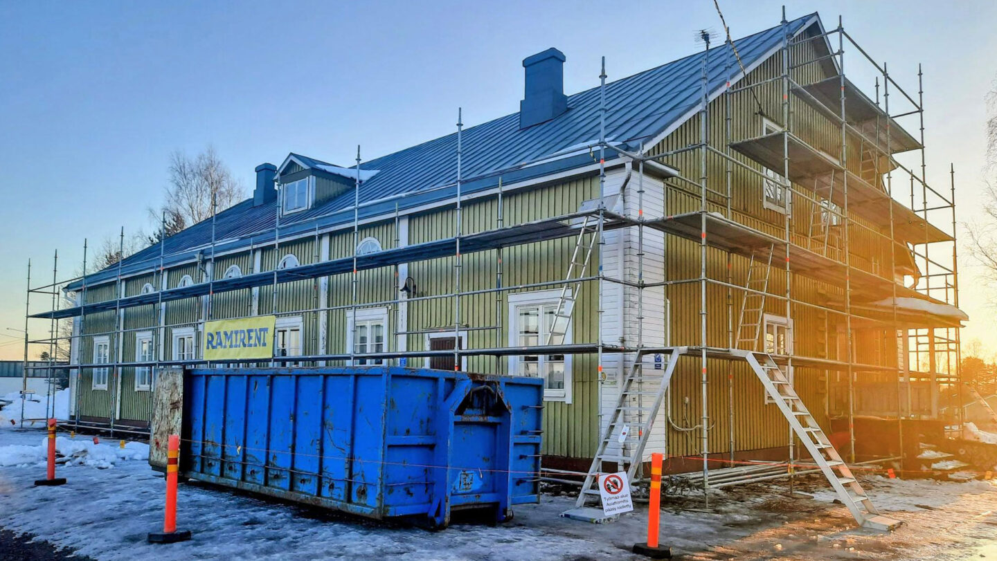 Vanha vihreä isohko puurakennus jonka ympärille on kasattu rakennustelineet.