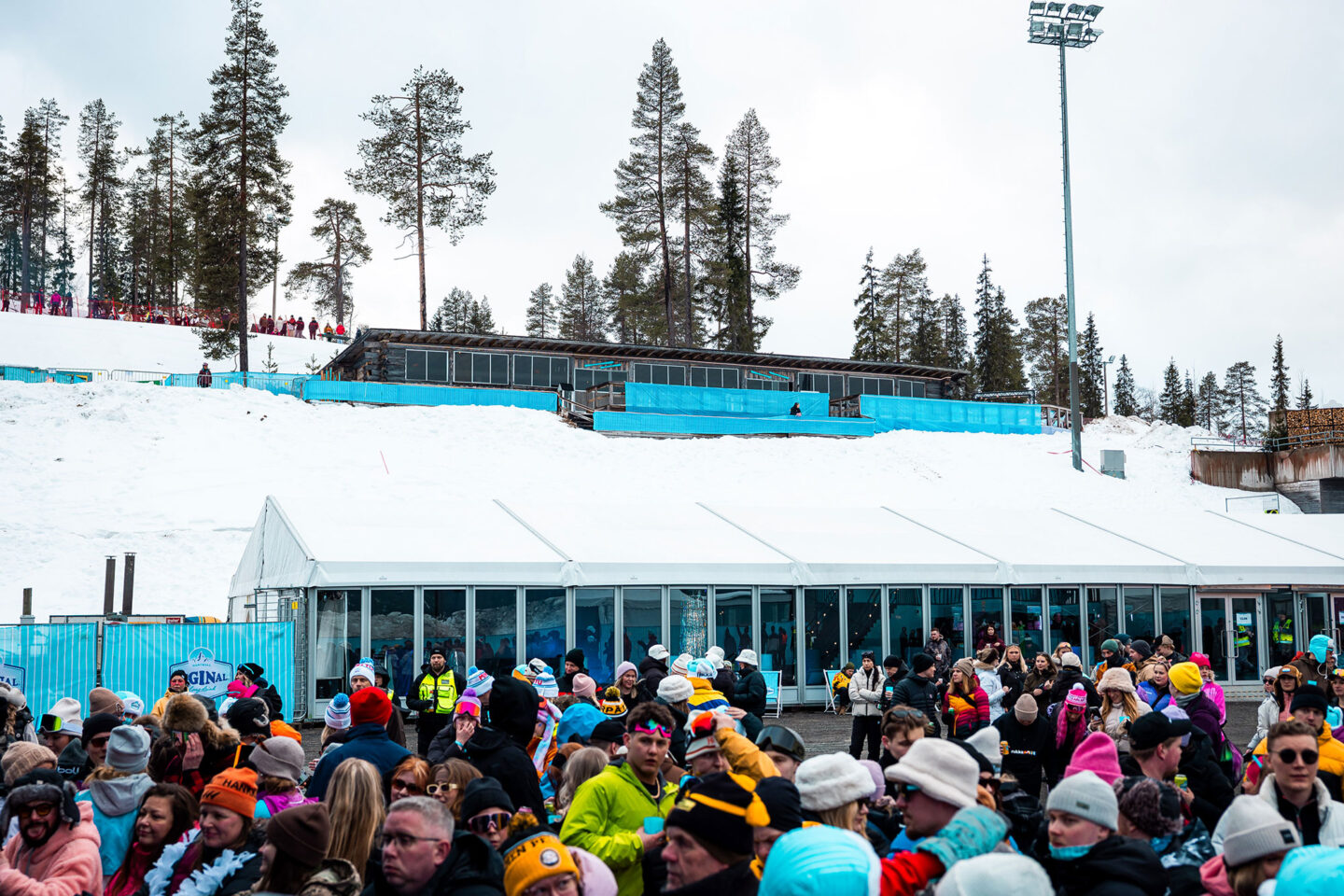 Ison tapahtumateltan edessä on paljon ihmisiä talvisessa maisemassa.