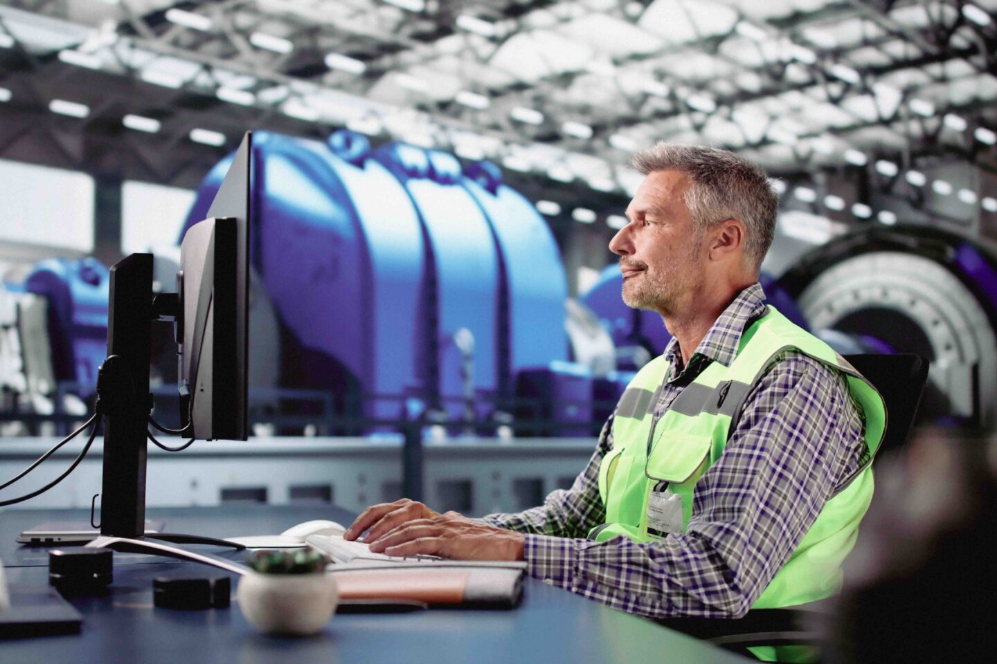 Henkilö käyttää tietokonetta teollisuusympäristössä.