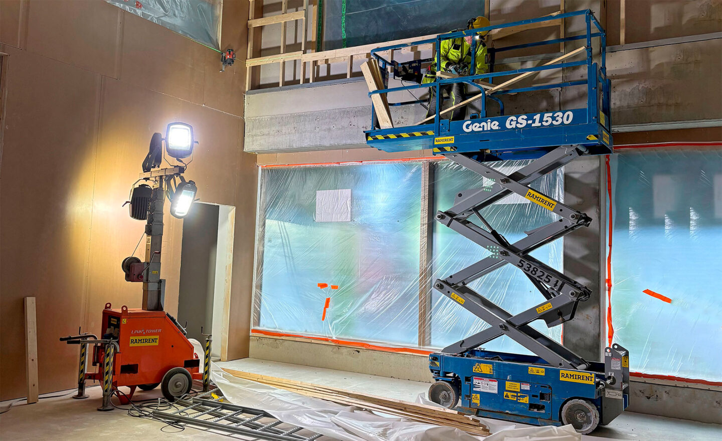 Työmaan sisäkuva jossa näkyy valomasto sekä sininen saksinostin kori ylhäällä.